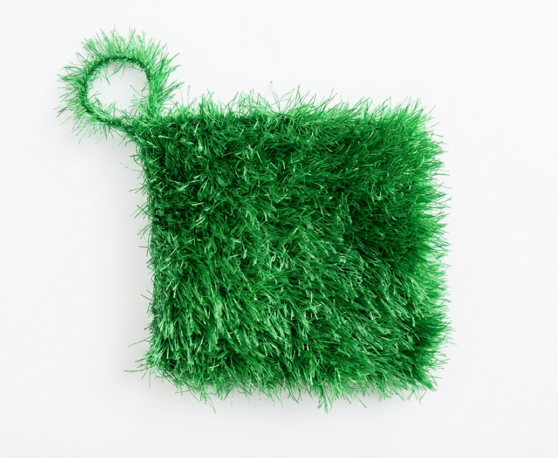 Green textured loofah scrubber with a hanging loop, laid flat on a white background