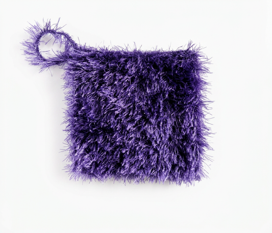 Purple textured loofah scrubber with a hanging loop, laid flat on a white background
